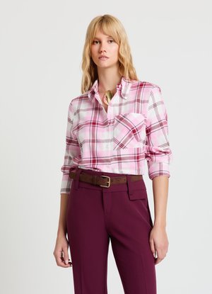 Chemise à carreaux rose avec col boutonné, comprenant une poche poitrine et des manches retroussées, associée à un pantalon bordeaux foncé sur mesure et une ceinture marron.