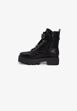 Stivale alla caviglia in pelle nera con suola in gomma spessa, punta rotonda, lacci frontali, chiusura con zip e cinturino regolabile con dettaglio del logo.