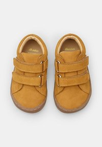 Chaussures en suède tan avec deux bandes Velcro et une semelle en caoutchouc. Design à bout arrondi avec des accents cousus et une doublure intérieure douce.
