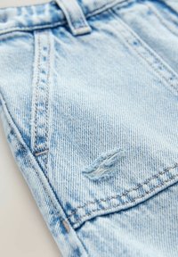Shorts de mezclilla azul claro con un sutil detalle desgastado, con costuras y bolsillos visibles, que muestran un acabado de tela texturizada.