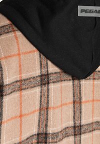 Huvtröja med en beige och orange rutmönstrad ulltextur, med en svart tygkappa och en silvrig "PEGADA" logotags.