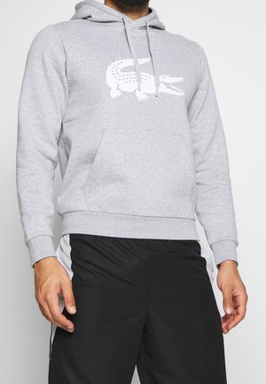 Grijze katoenen hoodie met een witte krokodilafbeelding op de borst, voorzien van een capuchon met trekkoord en een voorzak in kangoeroestijl.