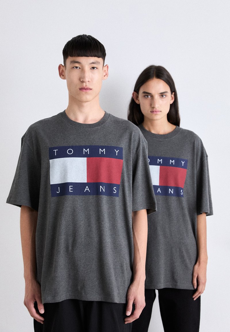 Camisetas de algodón gris con un diseño a bloques de color que presenta acentos en navy, blanco y rojo. Corte relajado y mangas cortas, mostradas en dos modelos.