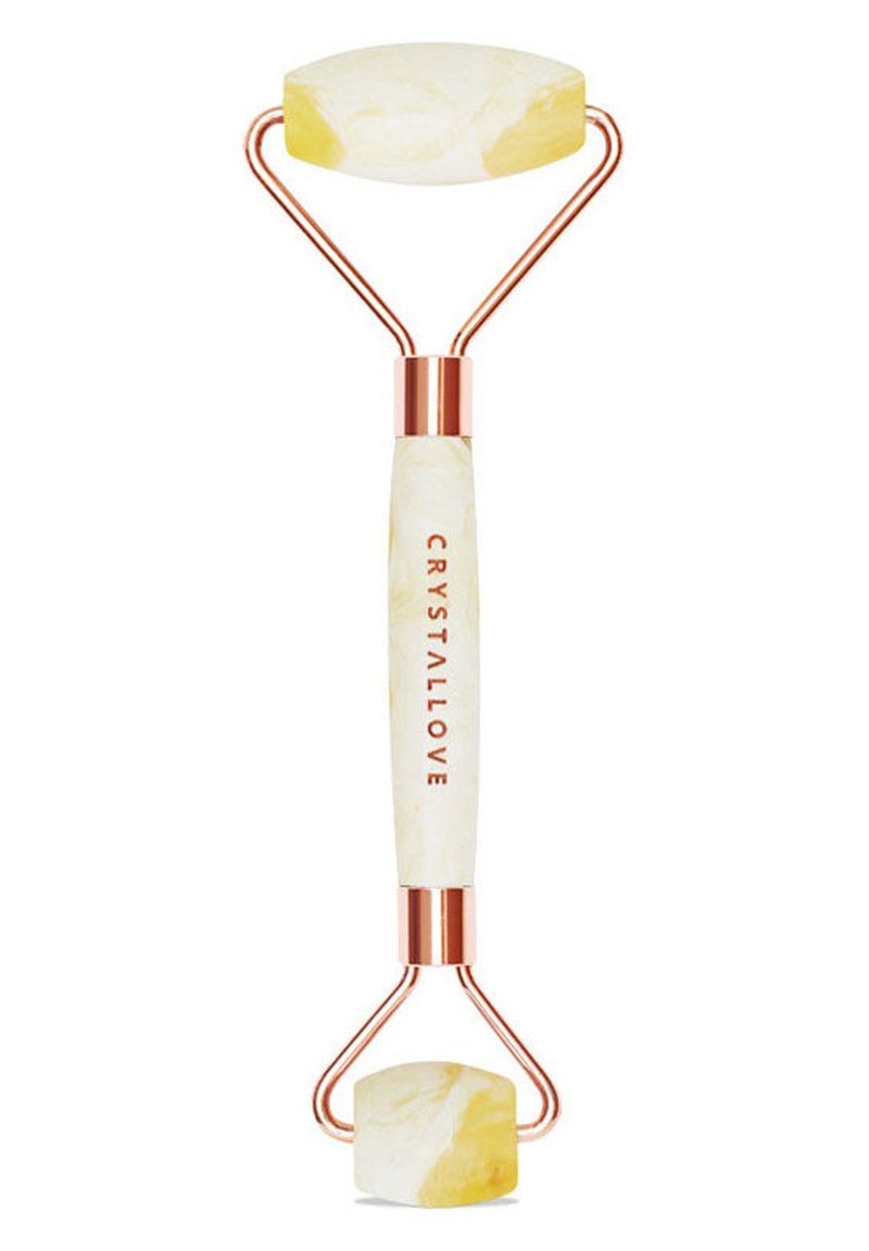 Rullo di giada con due teste di pietra gialla marmorizzata, hardware in oro rosa e un manico bianco che presenta il testo "CRYSTALLOVE."