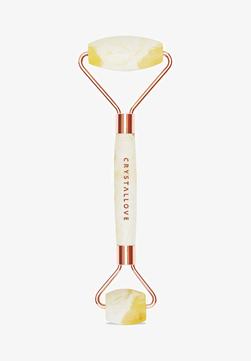 Rullo di giada con due teste di pietra gialla marmorizzata, hardware in oro rosa e un manico bianco che presenta il testo "CRYSTALLOVE."