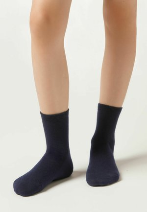 Navyblaue Baumwollsocken in mittlerer Wadenhöhe, mit glatter Textur und geripptem Bündchen, auf einem neutralen Hintergrund präsentiert.