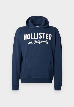 Navy blue hoodie made of cotton blend, featuring a kangaroo pocket, ribbed cuffs, and large white printed text: "HOLLISTER So. California."