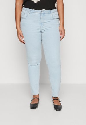 Light blue skinny jeans made of denim, featuring a classic five-pocket design and visible stitching. Worn with flat black shoes.