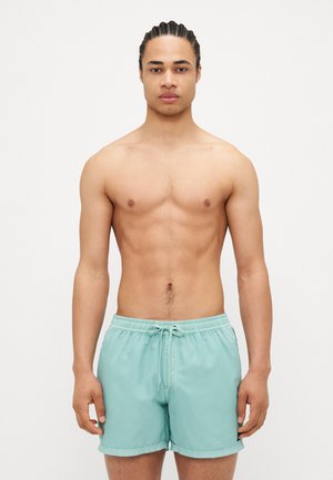 Turquoise swim shorts made of lightweight fabric, elastic waistband with drawstring, and a simple, unadorned design.
