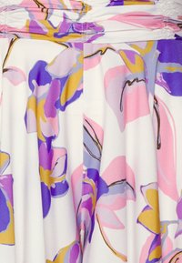 Blommig klänning med vit bakgrund och abstrakta blommönster i lila, rosa och gult. Slät, lätt tyg med samlad detalj vid midjan.