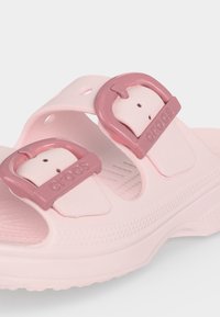 Sandale Crocs rose clair avec deux boucles réglables rose foncé et une semelle texturée pour le confort et l'adhérence.