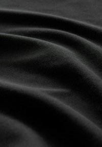 Tissu noir avec une texture lisse, affichant des vagues douces et un éclat subtil, soulignant une apparence élégante et drapée.