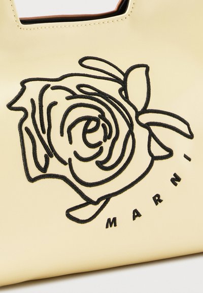 Επιφάνεια από δέρμα κρεμ με μαύρο κεντητό τριαντάφυλλο και μερικό κείμενο "MARNI" από κάτω.