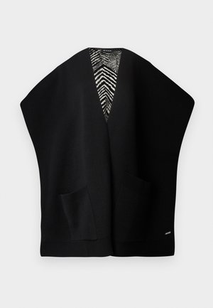 Black knit cardigan with a deep V-neck, wide sleeves, two front pockets, and a contrasting black-and-white zigzag pattern on the interior.