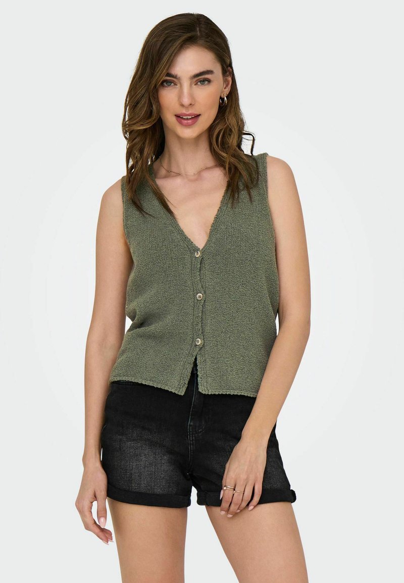 Cardigan in maglia senza maniche verde oliva con scollo a V, bottoni frontali e tessuto testurizzato. Abbinato a pantaloncini in denim neri.