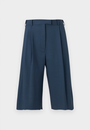 Pantaloni largi, cropați, de culoare bleumarin, cu pliuri frontale, bucle pentru curea și închidere frontală ascunsă, pe un fundal simplu.