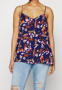 Kukallinen toppi tummansinisessä, jossa on V-pääntie, ohut olkaimet ja rento leikkaus. Kangas esittelee eloisia vaaleanpunaisia, oransseja ja sinisiä kukkakuoseja.