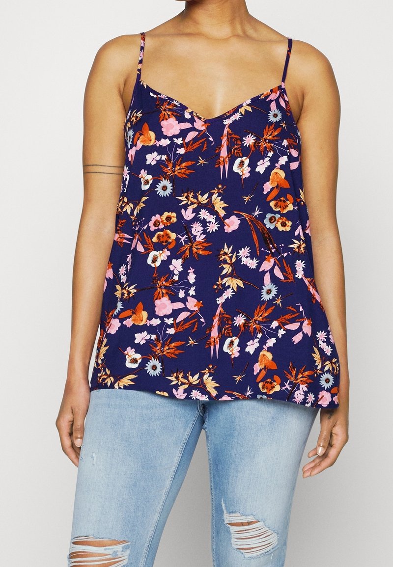 Kukallinen toppi tummansinisessä, jossa on V-pääntie, ohut olkaimet ja rento leikkaus. Kangas esittelee eloisia vaaleanpunaisia, oransseja ja sinisiä kukkakuoseja.