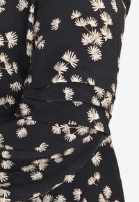 Tessuto nero con stampa floreale in crema e accenti azzurri. Presenta plissettature e una texture liscia. Il design include piccoli margherite.