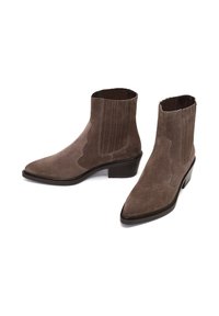 Stivali alla caviglia in pelle scamosciata marrone con punta a punta, pannelli elastici laterali e tacco basso a blocco. Caratterizzati da una texture liscia e dettagli di cuciture sottili.