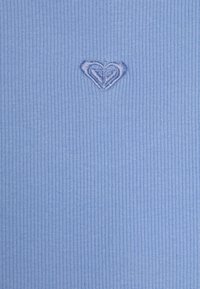 Ljusblått ribbat tyg med en liten hjärtformad broderad detalj i mitten. Texturen är mjuk och slät.