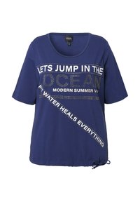Navyblauwe t-shirt met korte mouwen en een ronde hals, voorzien van witte tekst en versieringen, inclusief een zijstrikdetail aan de onderrand.