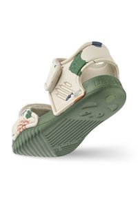 Sandals made of light-colored synthetic material with a green rubber sole, featuring a Velcro strap and colorful decorative patterns.