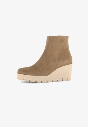 Botte à talon en wedge hauteur de cheville avec tige en daim beige et épaisse semelle en caoutchouc crème avec de profonds canaux pour une meilleure adhérence.