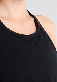 Svart träningslinne med rundad halsringning, slät textur och röda detaljer på axelbanden. Materialet verkar lätt och andas.