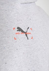 Pilkas taškuotas džemperio audinys turi juodą puma logotipą ir tekstą "REDUCE, REUSE, REGENERATE" oranžine spalva priekyje.