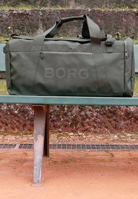 Ελαιόχρωμη τσάντα duffel φτιαγμένη από ανθεκτικό ύφασμα, με φερμουάρ τσέπη, δύο χερούλια και ανάγλυφο λογότυπο "BORG".