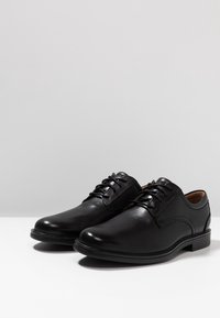 Chaussures de ville en cuir noir avec une finition lisse, bout arrondi et design à lacets. Présentent des détails cousus et un léger talon pour plus de soutien.