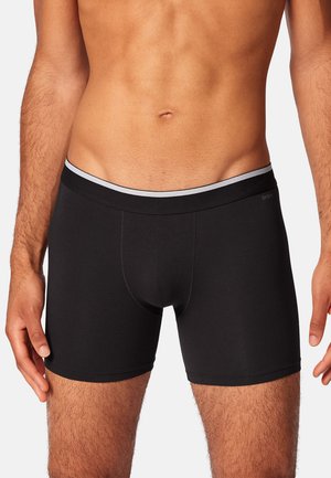 Boxers noirs avec une ceinture grise douce et élastique. Le tissu semble lisse et extensible, conçu pour le confort et l'ajustement. Aucun motif visible.