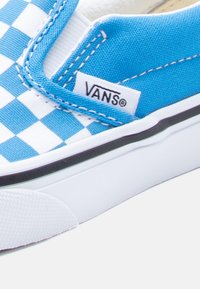Κανάβινο αθλητικό παπούτσι με μπλε και λευκό σχέδιο σκακιέρας, ελαστικές πλαϊνές λεπτομέρειες, λευκή λαστιχένια σόλα και μαύρη επένδυση, με ετικέτα λογότυπου Vans.