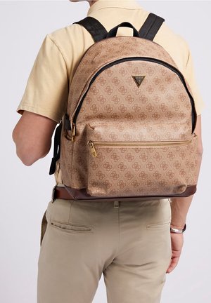 Sac à dos marron à motifs avec des accents noirs, forme structurée, poche zippée à l'avant et détails du logo en haut. Bretelles noires ajustables.