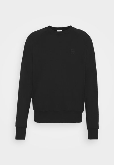 Sweatshirt noir en mélange de coton, présentant un col rond côtelé, des manches raglan et un petit logo en relief sur la poitrine.