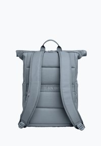 Grey padded backpack with adjustable straps, roll-top design, and side pockets. Features textured fabric and a central logo strap.