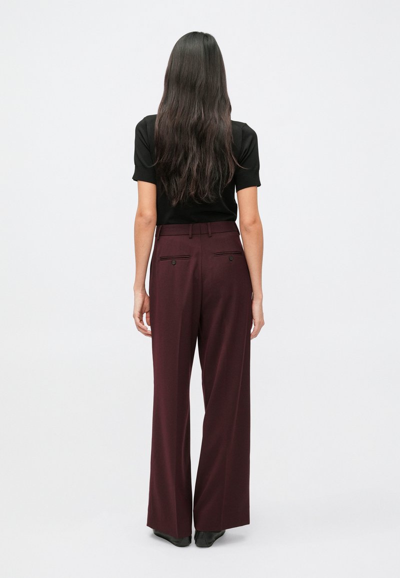 Burgundy wide-leg trousers with a high waist, tailored design, and back pockets. Pairing with a fitted black short-sleeve top.