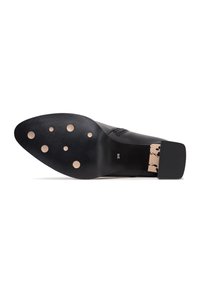 Semelle de chaussure noire élégante avec six inserts beige circulaires antidérapants et un talon carré bloc, taille marquée 39 sur la zone de la voûte plantaire.