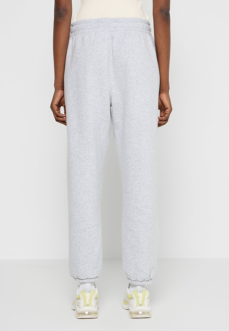 Jasnoszare spodnie dresowe wykonane z miękkiego materiału, z elastycznym pasem, zwężanymi mankietami i kieszeniami bocznymi.