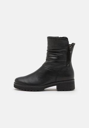 Zwarte leren enkellaars met een slouchdesign, zijrits en een getextureerde rubberen zool. Heeft een lage blokhak en minimale stiksels.