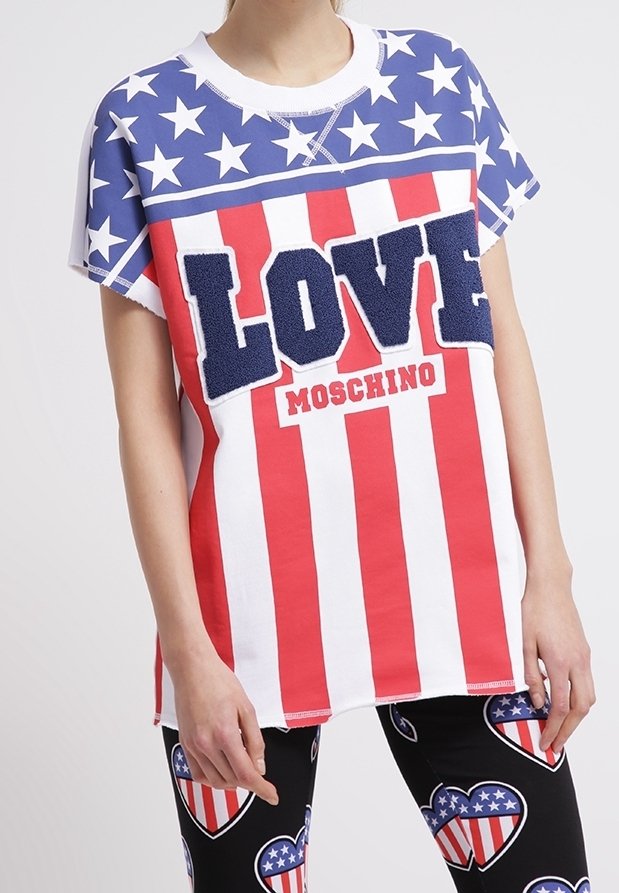 Personne portant un t-shirt rouge, blanc et bleu avec des étoiles et des rayures, le texte "LOVE MOSCHINO", et des leggings noirs avec des motifs en forme de cœur représentant le drapeau américain.