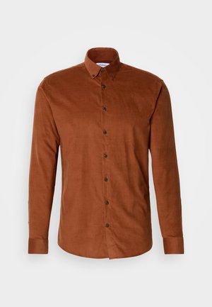 Chemise boutonnée en velours côtelé marron avec un col, des manches longues et des boutons foncés sur le devant, présentant une texture lisse.