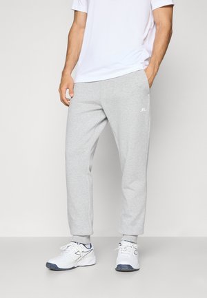 Gray sweatpants in a relaxed fit, made of a soft material, featuring a small white logo on the left thigh, paired with white athletic shoes.