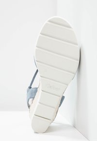 Light blue suede sandal with a textured white rubber sole. Features an adjustable strap and a woven jute-like accent on the heel.