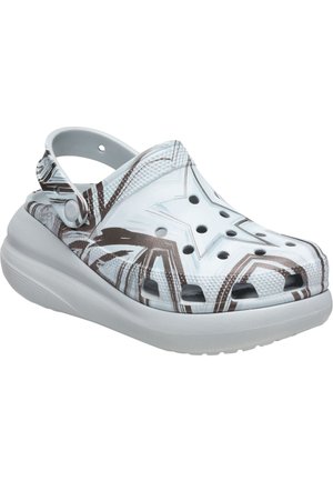 Sabot blanc avec semelle surélevée, trous de ventilation et motifs étoiles et géométriques marron, doté d'une bride de talon mobile.