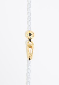 Ketting van parelmoeren kralen met een gouden sluiting en een ronde hanger, versierd met gekleurde iconen en een centrale zwarte hart.