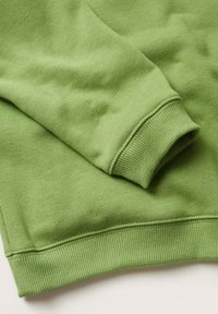 Manche verte de sweat-shirt à manches longues avec bord-côtes au poignet et à l'ourlet, montrant la texture du tissu et les détails des coutures.