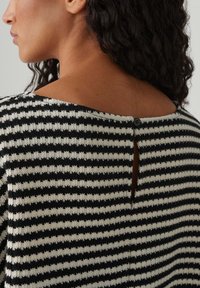 Top lavorato a maglia con strisce alternate nere e crema, schiena scoperta con chiusura a bottone e finitura testurizzata.