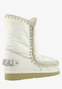 Stivale alla caviglia in pelle bianca con superficie texturizzata, bordo intrecciato e un accento decorativo di strass sul tallone. Suola in gomma.
